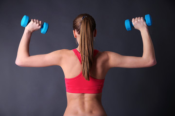 Young beautiful fitness girl exercising with dumbbells,