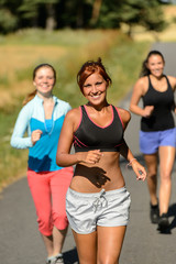 Friends jogging together outdoors sunny path