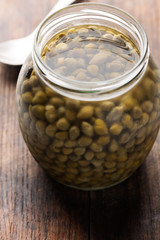 capers in glass jar on wood