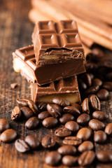 Chocolate candy bar and cofee beans on wooden table close up