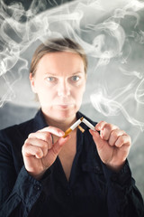 Fototapeta premium Woman quits smoking and breaking cigarette in half