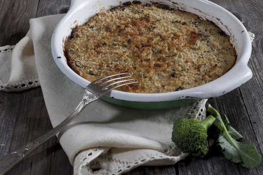vegetables au gratin on casserole with fork on wooden table