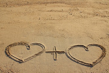 Fototapeta na wymiar Couple of hearts shape drawn on beach sand