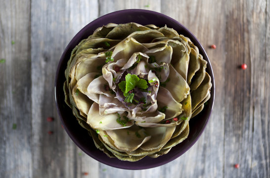 artichoke like lotus flower with parsley and peppercorns on bowl