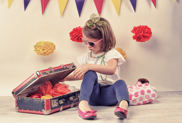 little girl playing with a little retro suitcase