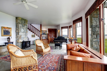 Spacious stone living room with piano and antique stove style fi