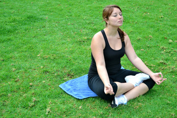 Fototapeta na wymiar Young woman practicing yoga in the park