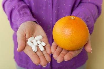 Woman hand with pills medicine tablets and grapefruit