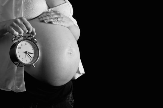 Pregnant woman holding a clock