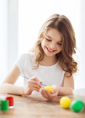 Obraz na płótnie Canvas smiling little girl coloring eggs for easter