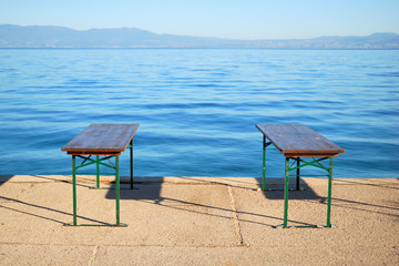 Calm blue sea and two benches on the bank