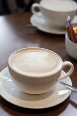 A latte coffee in a white cup with saucer