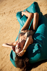 Beautiful young seductive sexy brunette lying on the beach - obrazy, fototapety, plakaty