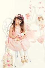 little girl with soft toy sitting on a chair