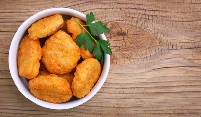 Chicken nuggets in bowl on wooden background