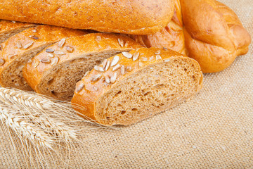 Assortment of baked breads with spikelets of wheat on burlap