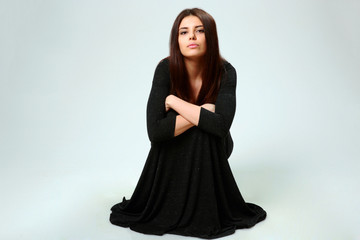 woman in black dress sitting on the floor on gray background