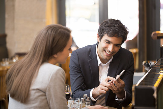 In a restaurant cheerful couple surfing the web on smartphone