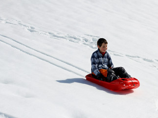 Fototapeta na wymiar kid down the descent with red bob on white snow