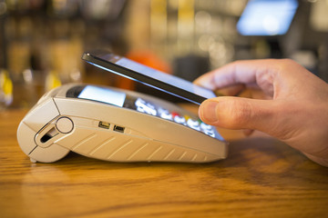 Man paying with NFC technology on mobile phone, restaurant, shop