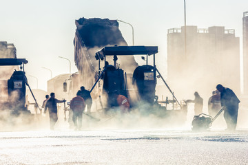 Workers making asphalt with shovels at road constructio - obrazy, fototapety, plakaty