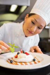 Obraz na płótnie Canvas Concentrated female chef garnishing food