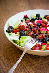 Fresh vegetable salad on a plate with vintage wooden background