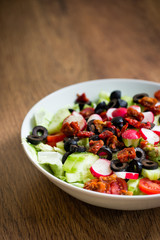 Fresh vegetable salad on a plate with vintage wooden background