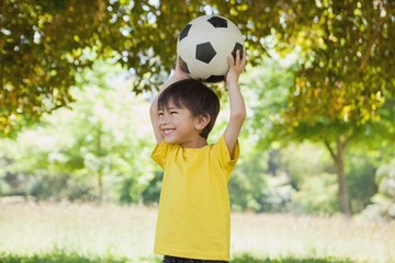 Obraz premium Little boy holding up football at park