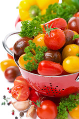 Assorted cherry tomatoes in a colander, spices and fresh herbs