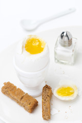 soft-boiled egg, salt and toast on a plate, vertical