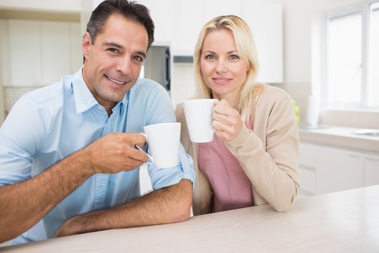 Portrait of happy couple with coffee cups in kitchen