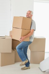 Smiling man carrying cardboard moving boxes