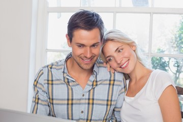 Happy loving couple with laptop at home