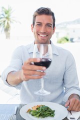 Smiling young man with wine glass having food