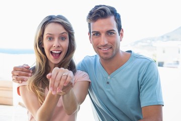 Obraz premium Cheerful woman showing engagement ring besides man