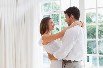 Side view of loving couple embracing at home