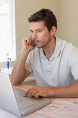 Fototapeta premium Man using laptop and mobile phone at home