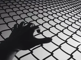 Foto op Plexiglas Hand holding wire fence in black and white © Nuchylee