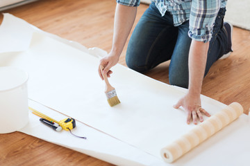 closeup of male hands smearing wallpaper with glue
