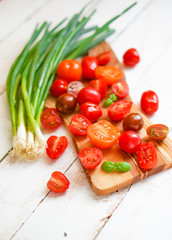 Colorful tomatoes on board on wooden background
