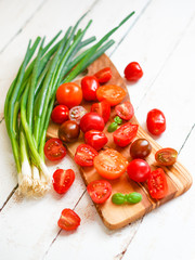 Colorful tomatoes on board on wooden background