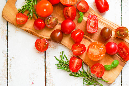 Colorful tomatoes on board on wooden background