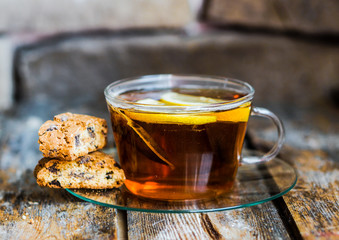 Tea cup with lemon and cookies on rustic wooden background