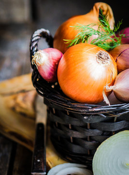 Colorful onions in the basket on rustic wooden background