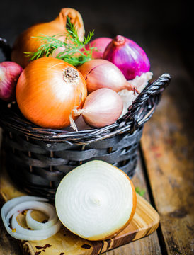 Colorful onions in the basket on rustic wooden background