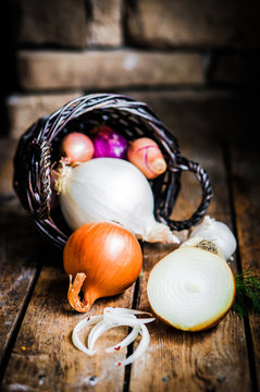 Colorful onions in the basket on rustic wooden background