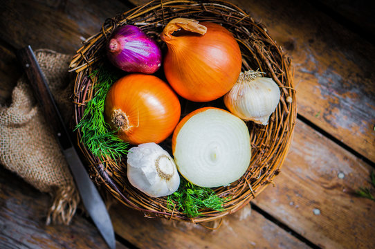 Colorful onions and garlic in the basket on rustic wooden backgr