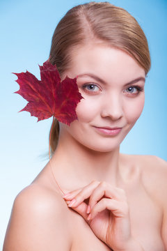 Skin care. Portrait of young woman girl with red maple leaf.