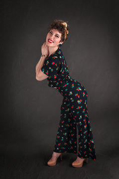 Pinup Girl in Flowered Outfit Stands Against Grey Background